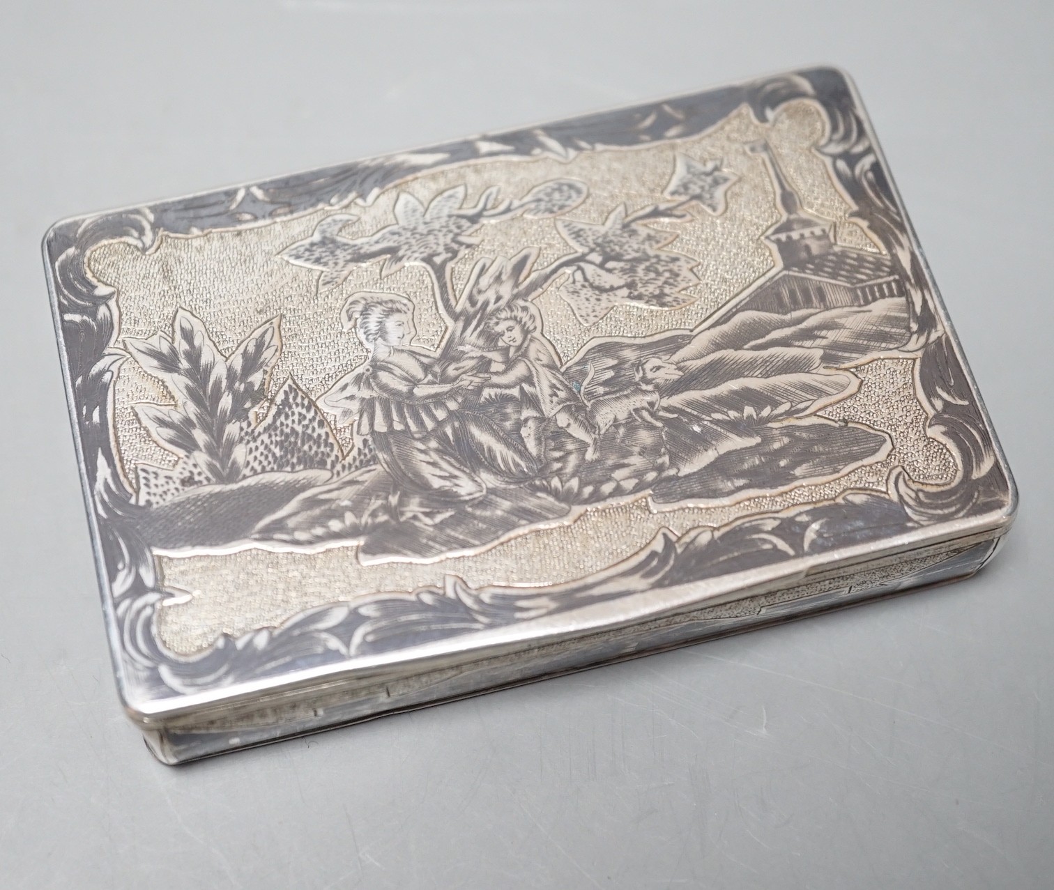 A late 19th century Russian 84 zolotnik and niello snuff box, decorate with figures in a landscape, 85mm.